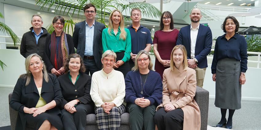 The image shows a group of professionals posed together in an office setting